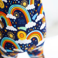 The Second-Skin Convertible Romper Here Comes the Sunshine (Blue) with rainbow, sun, and cloud print.