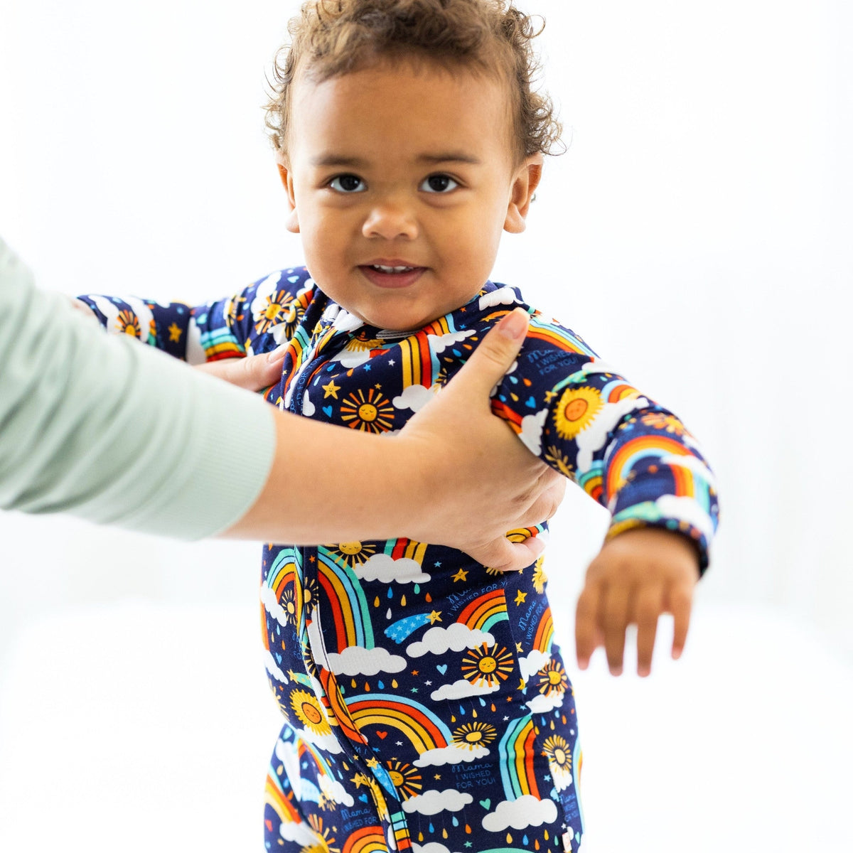 Baby in Here Comes the Sunshine blue Second-Skin Convertible Romper with sun and rainbow print.