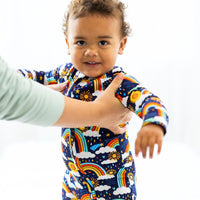 Baby in Here Comes the Sunshine blue Second-Skin Convertible Romper with sun and rainbow print.