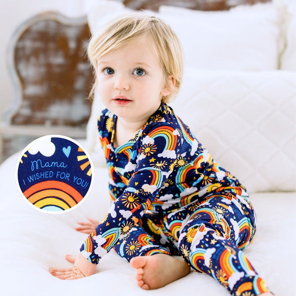 Child in Here Comes the Sunshine Blue two-piece long-sleeve pajama with rainbow sun print.