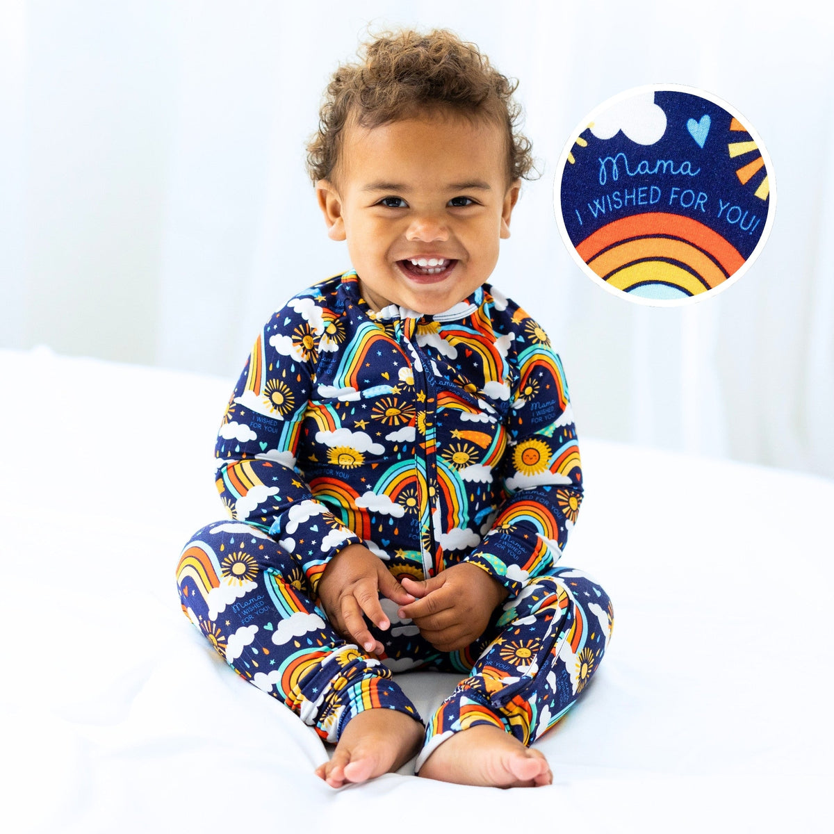 Baby in blue Here Comes the Sunshine Second-Skin Convertible Romper with rainbow and sun print.