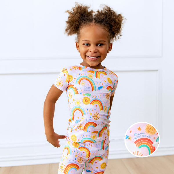 Girl wearing The Second-Skin 2-Piece Short Sleeve Pajama in pink with sun and rainbow print.