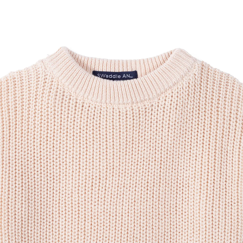 Close up of beige organic cotton chunky knit romper showing navy SwaddleAn label