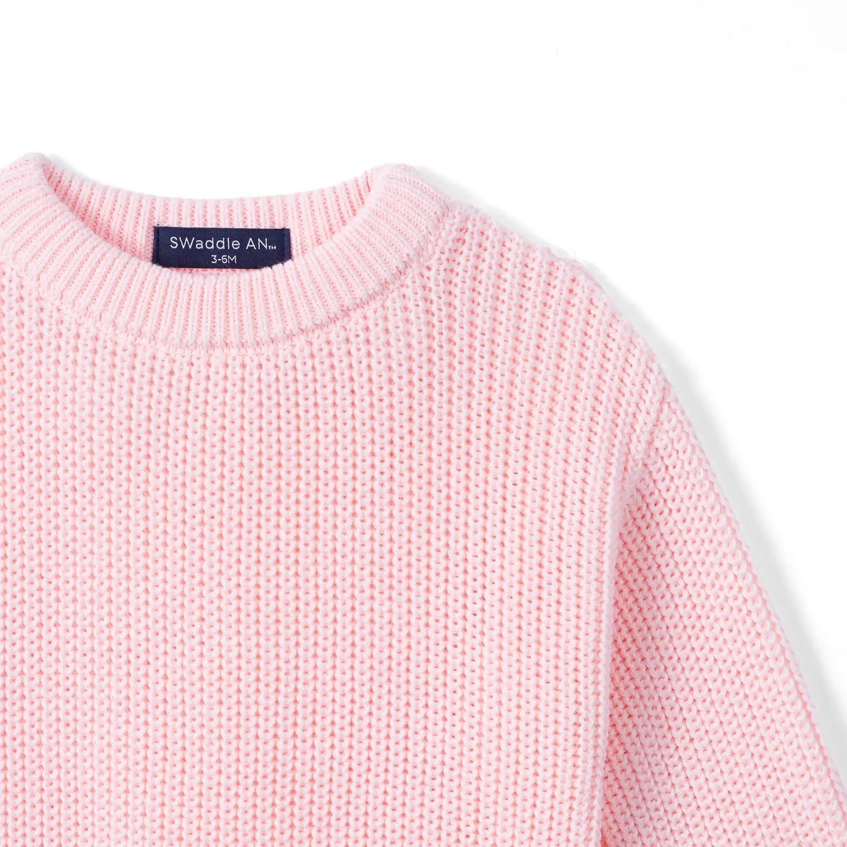 Detail of pink romper shoulder showing ribbed crewneck collar and consistent chunky knit pattern