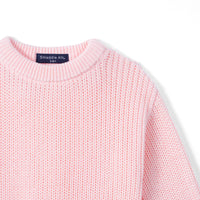 Detail of pink romper shoulder showing ribbed crewneck collar and consistent chunky knit pattern