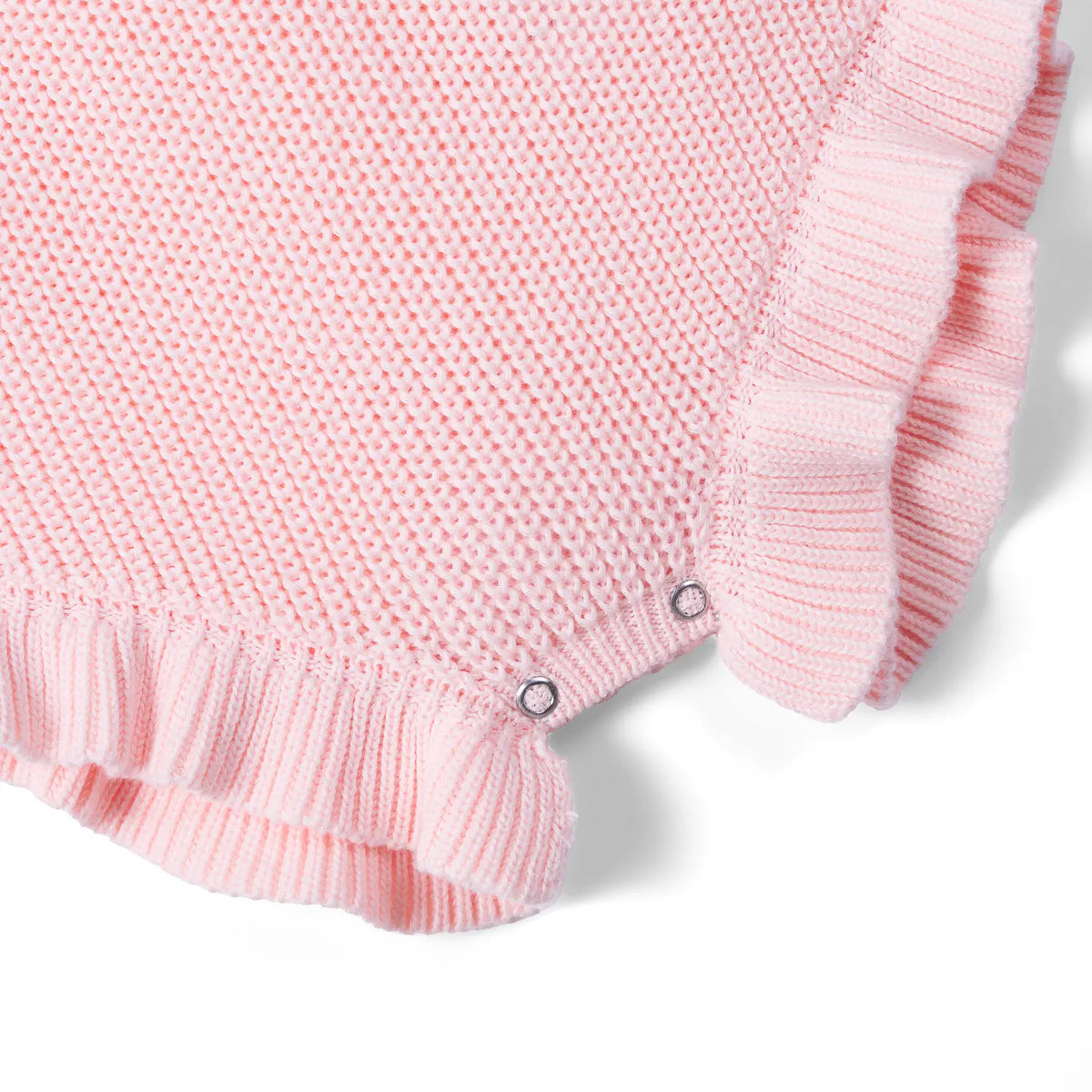 Bottom corner of pink romper showing reinforced metal snaps at crotch and ribbed ruffled hem