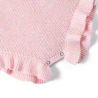 Bottom corner of pink romper showing reinforced metal snaps at crotch and ribbed ruffled hem
