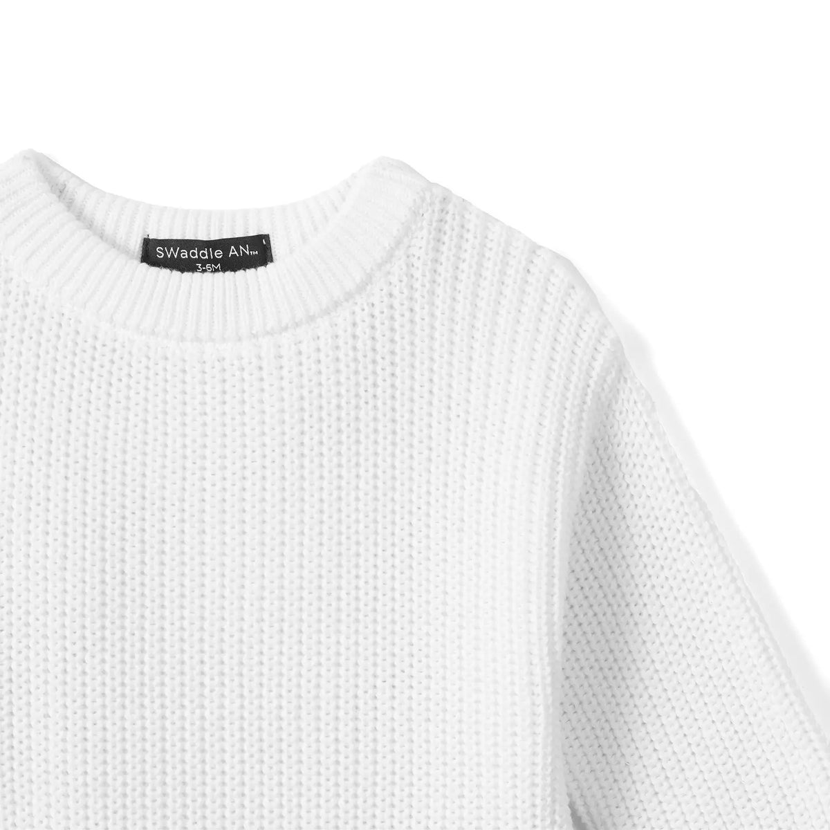 High-angle view of shoulder knit structure and black size tag stitching on white romper