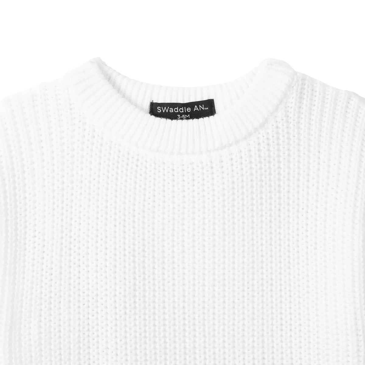 Close-up of white chunky knit texture and black SWaddle AN Inc label inside neckline