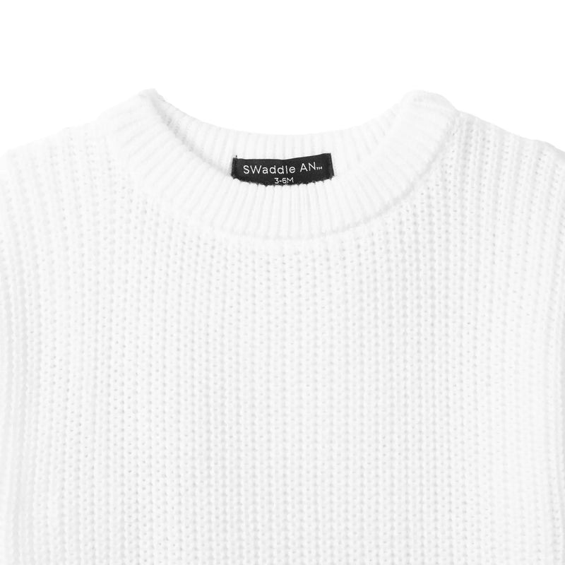 Close-up of white chunky knit texture and black SWaddle AN Inc label inside neckline