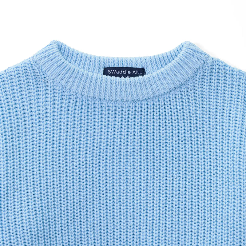 Close-up of ribbed crewneck collar showing navy Swaddle AN label with size 3-6M in white text