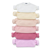 Stack of six chunky knit crewneck sweaters in gradient colors from white to lilac