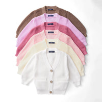 Stack of six SwaddleAn cardigans in various colors fanned out with white one showing buttons and pockets