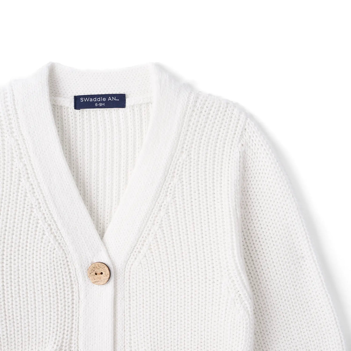Upper white cardigan section with V-neck collar, ribbed texture, wood button, and navy brand label