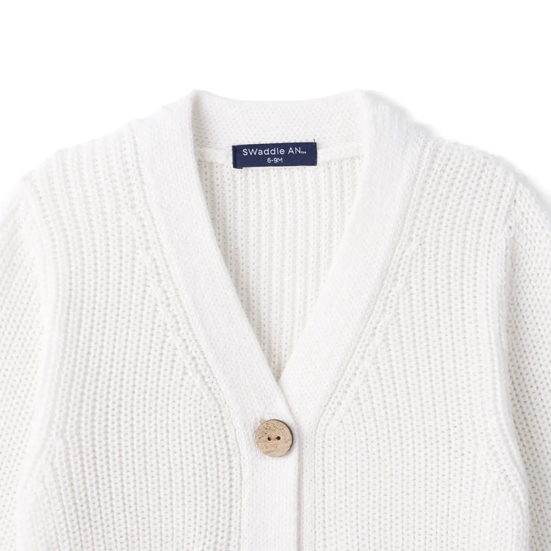 Close-up of white ribbed knit neckline showing top wooden button and navy SWaddle AN size tag