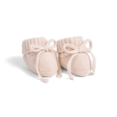 Light beige knitted baby booties with ribbed cuffs and decorative bows on white background