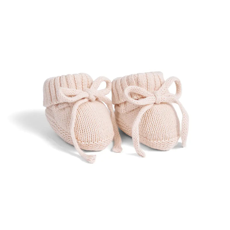 Light beige knitted baby booties with ribbed cuffs and decorative bows on white background