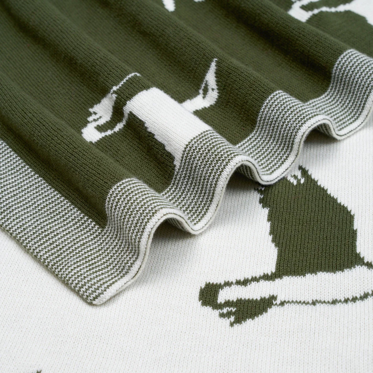 Macro view of green and white reversible jacquard knit baby blanket texture and ribbed border