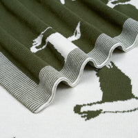 Macro view of green and white reversible jacquard knit baby blanket texture and ribbed border