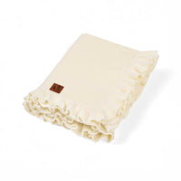 Folded cream ruffled knit baby blanket with brown swan logo patch on white background