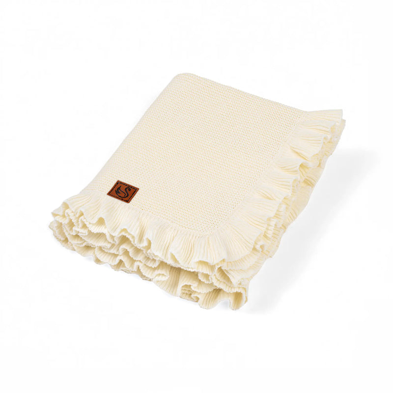 Folded cream ruffled knit baby blanket with brown swan logo patch on white background