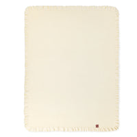 Flat-lay of cream waffle knit nursery blanket showing full rectangular shape and ruffled border