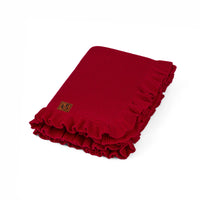 Folded deep red waffle stitch knit baby blanket with ruffled edges and visible brand label on white background