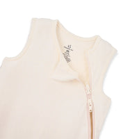 Close-up of SwaddleAn neck label and zipper pull on sand bamboo fabric