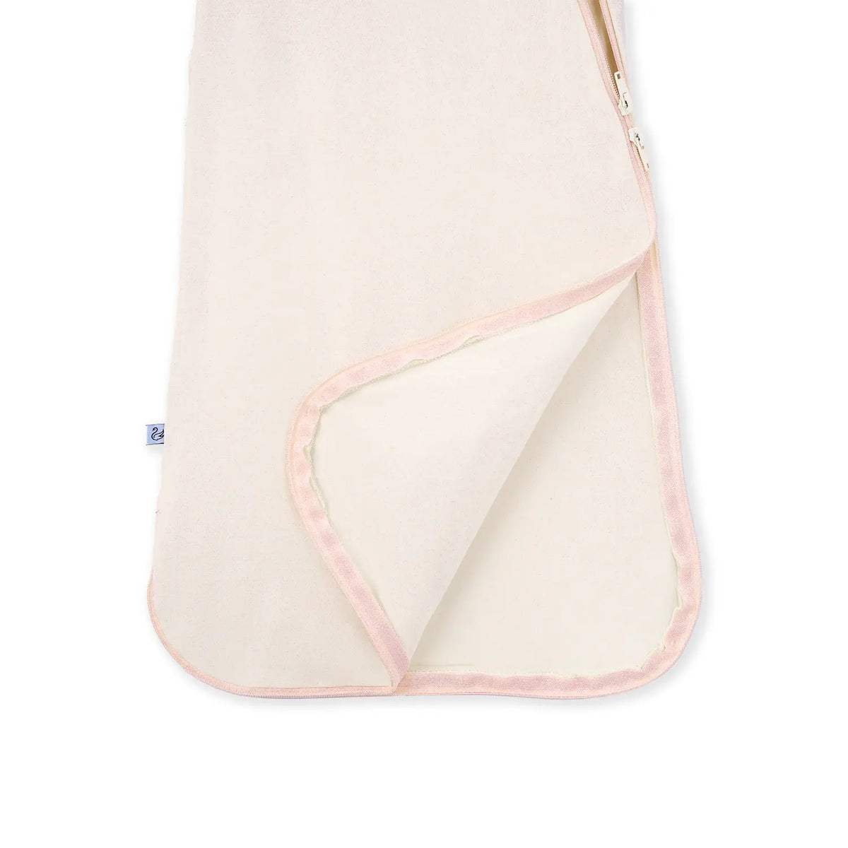 Lifted corner of sand bamboo sleep sack revealing inner lining and pink piped hem
