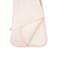 Lifted corner of sand bamboo sleep sack revealing inner lining and pink piped hem