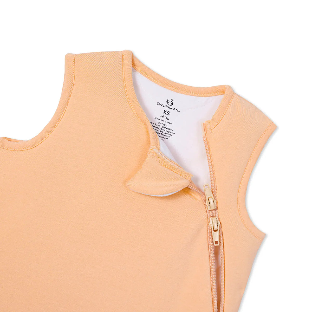 Close up of SWaddle AN~ brand label showing size XS and 1.0 tog rating on peach fabric