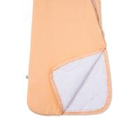 Outer peach fabric peeled back to reveal white quilted inner lining texture of baby sleep sack