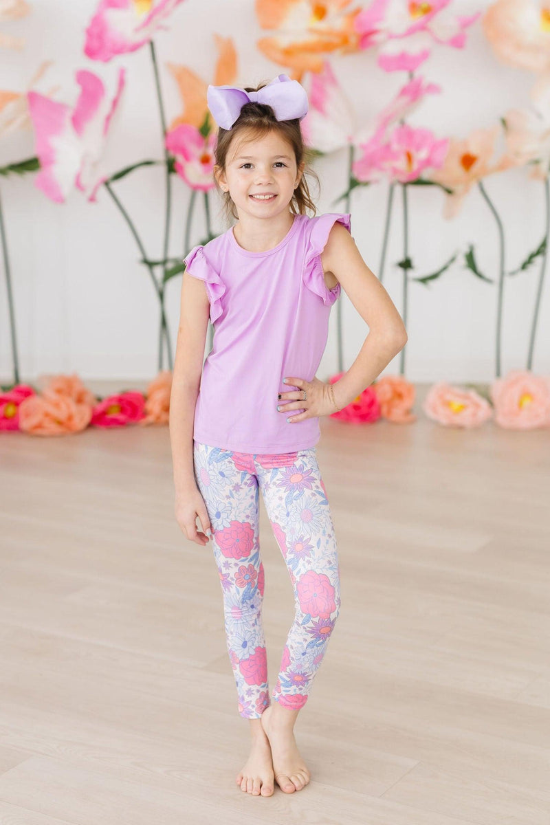 A child modeling Sweet Springtime Leggings and a matching top, highlighting the vibrant floral design and playful style for spring.