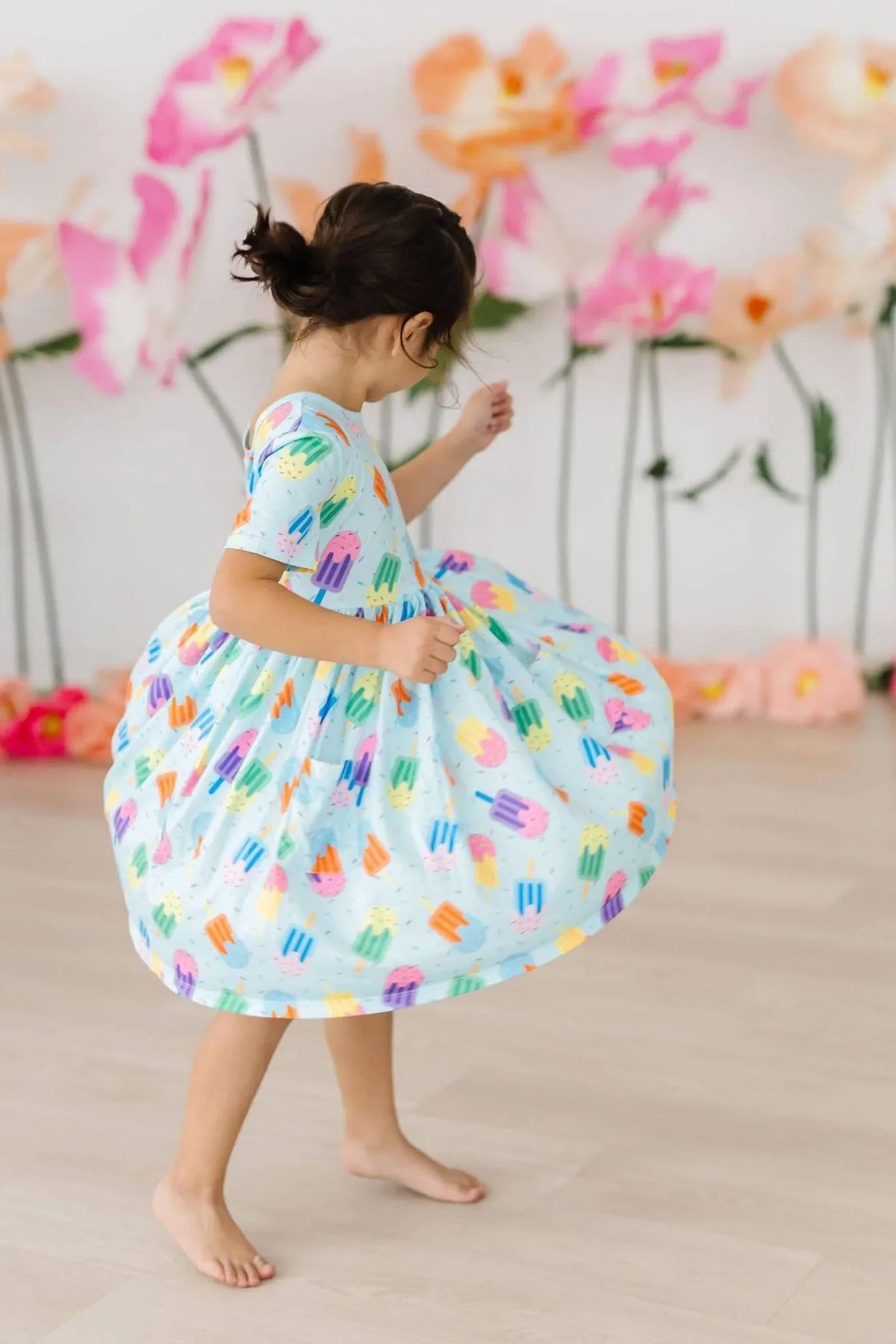 Toddler girl wearing a colorful popsicle print girls twirl dress with pockets, short sleeve and knee length