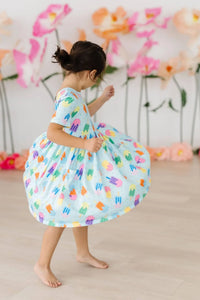 Toddler girl wearing a colorful popsicle print girls twirl dress with pockets, short sleeve and knee length