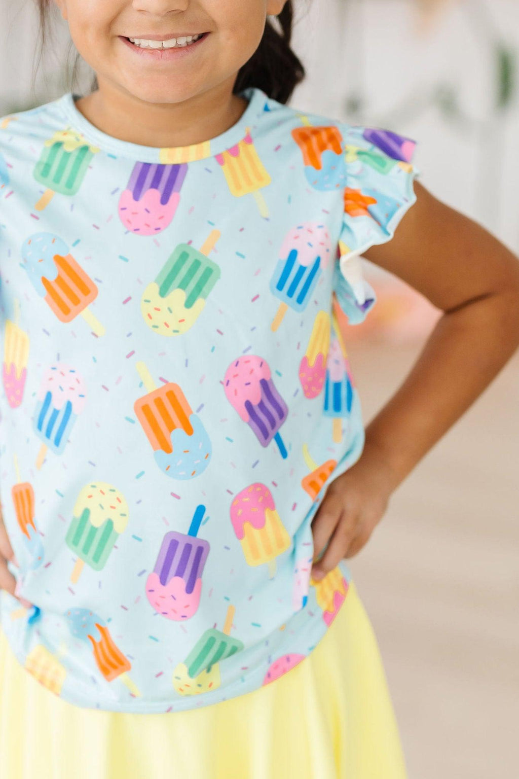 Adorable 'Sweet Treat' Ruffle Sleeve Tee for girls featuring colorful popsicle prints, perfect for playful outfits and summer fun.