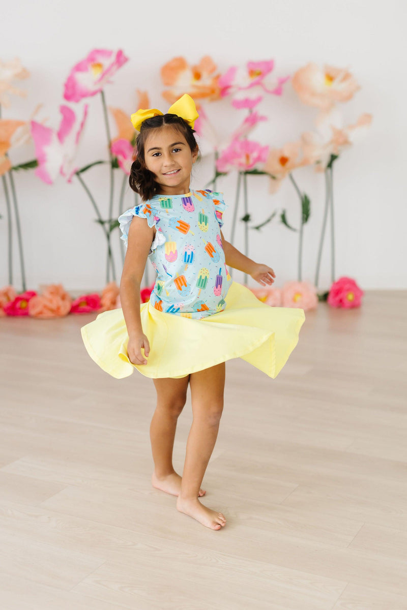 Little girl twirling in the Adorable 'Sweet Treat' Ruffle Sleeve Tee, highlighting vibrant popsicle designs and cheerful summer vibes.