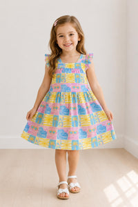 Child wearing Tropical Summer Ruffle Cross Back Dress in a pastel tropical print with ruffled shoulders.