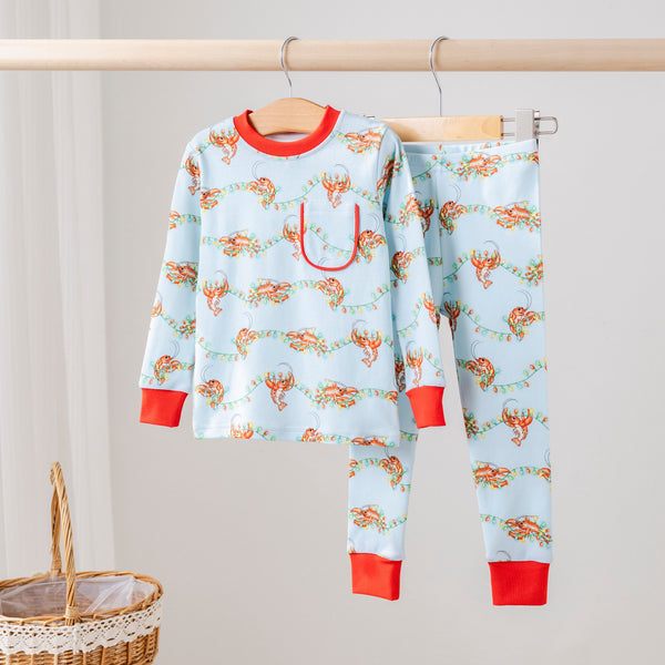 Twinkling Tails Organic Cotton Kids Pajamas in light blue with crawfish tangled in Christmas lights and red cuffs.