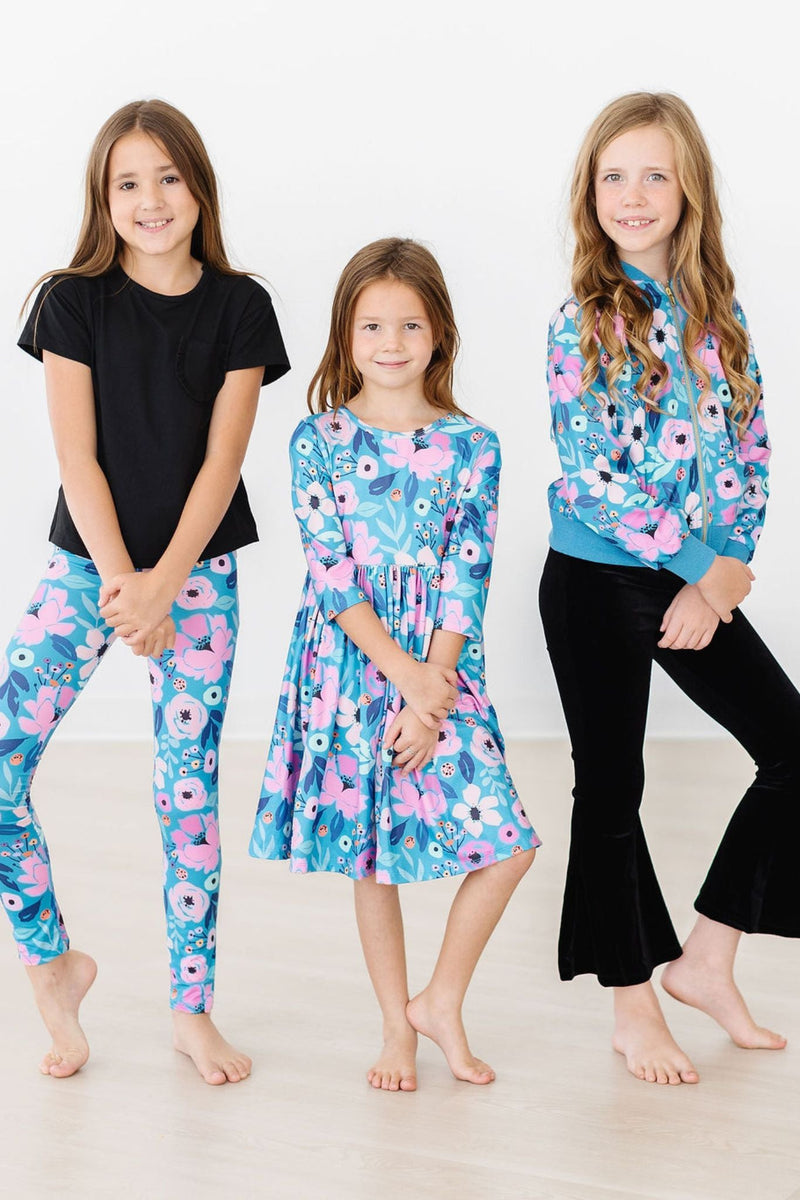 Three girls posing in different outfits, including the Twirling in Teal 3/4 Sleeve Pocket Twirl Dress by Mila & Rose, featuring playful styles and colorful designs.