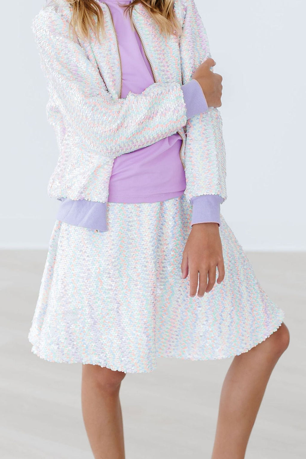 A young girl wearing the Unicorn Flip Sequin Twirl Skort paired with a light purple top, showcasing the dazzling flip sequins that sparkle with movement. Perfect for twirling and playful occasions!