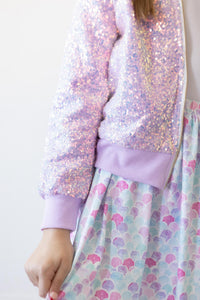 Lavender sequin jacket on a young girl, twirl-worthy sparkly outerwear with pastel dress.