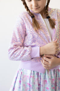 Girl wearing a lavender sequin jacket with braided hair and a pastel skirt.