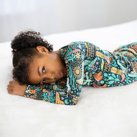 Child asleep on a white bed wearing The Second-Skin 2-Piece Long Sleeve Pajama | Wild West print.