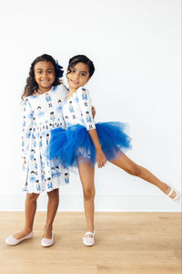 Girls pose in nutcracker print long sleeve dresses with full circle skirts and blue tulle twirl skirts.
