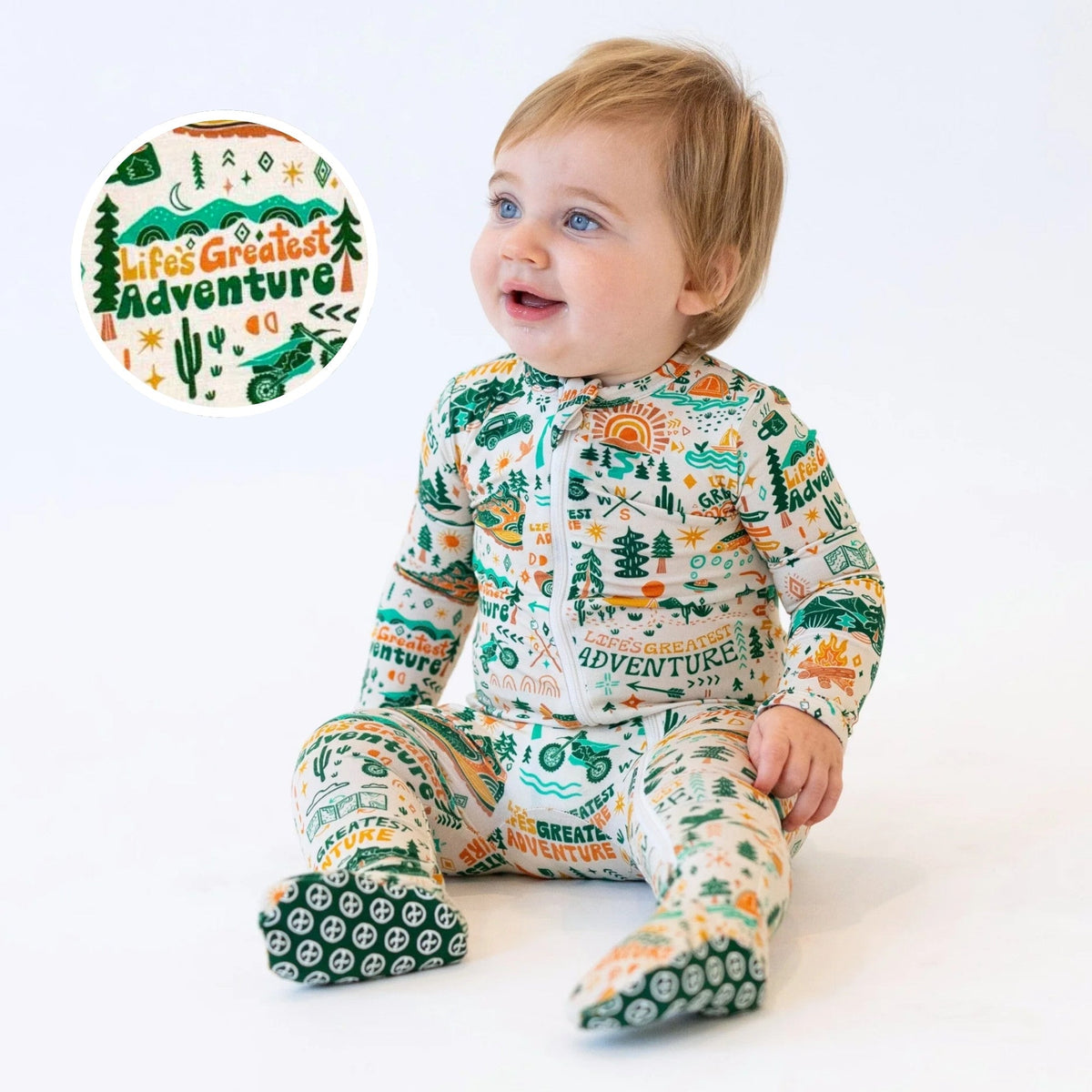 Baby wearing a onesie with 'Life's Greatest Adventure' print, sitting on a white background.