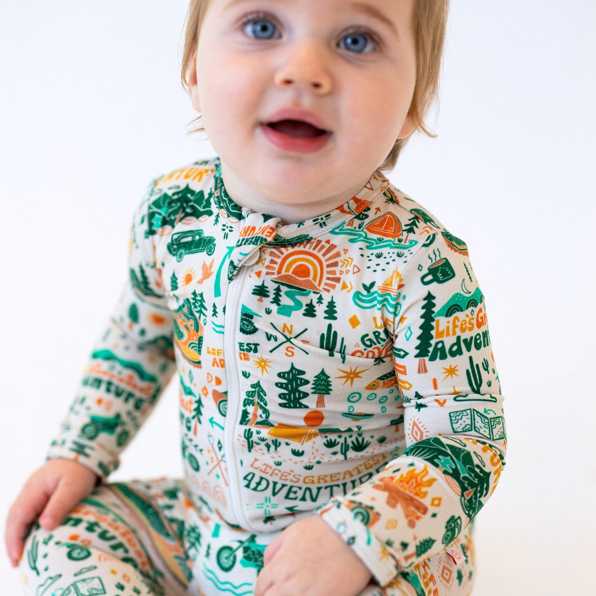 Baby wearing a colorful onesie with nature-themed design on a white background