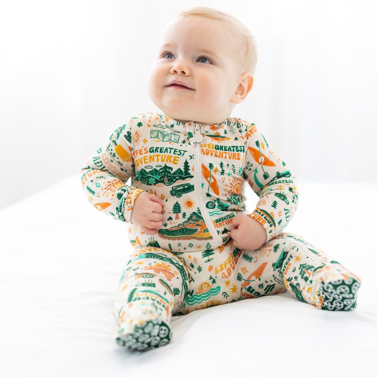 Baby wearing a onesie with adventure-themed design on a white background