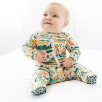 Baby wearing a onesie with adventure-themed design on a white background