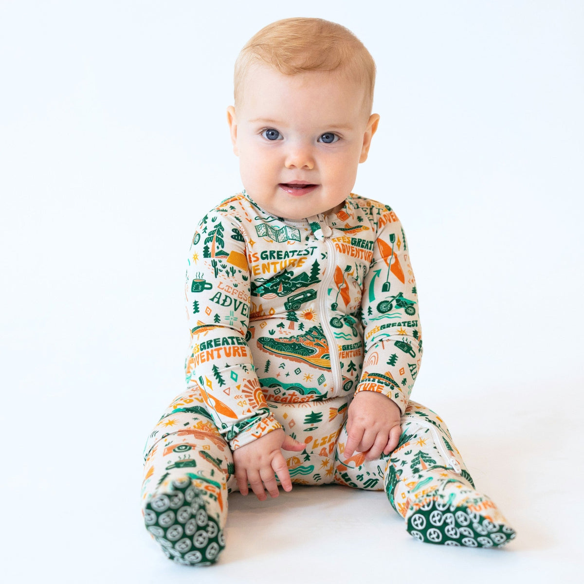 Baby wearing a colorful onesie with nature-themed print on a white background